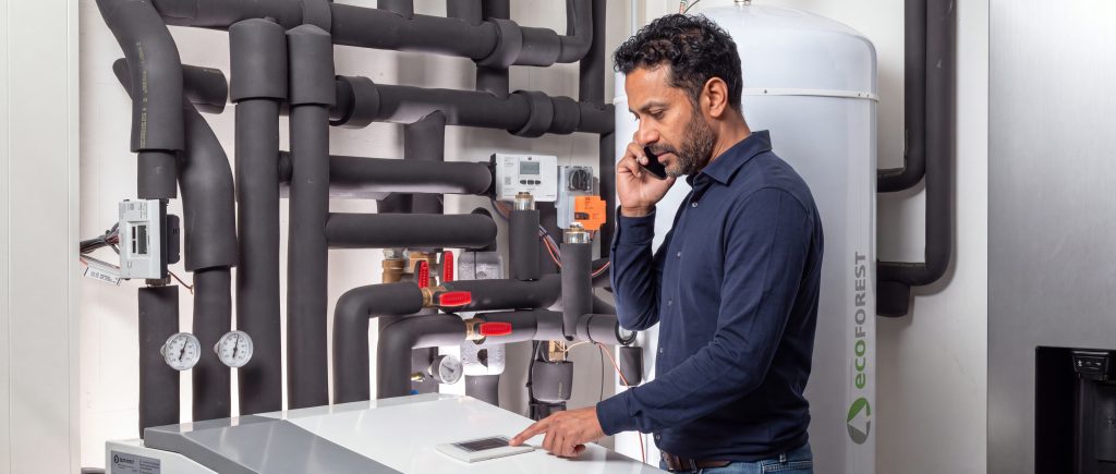 Man met headset werkt aan een verwarmingsinstallatie in een technische ruimte